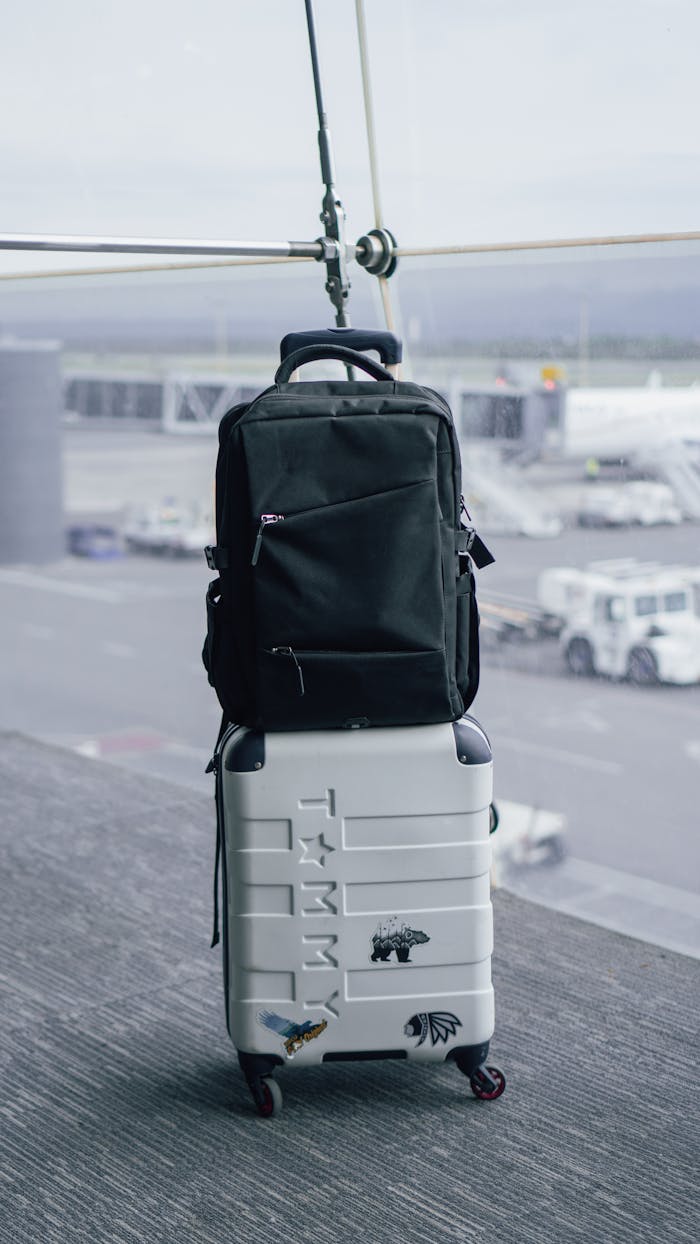 Crafting Captivating Headlines: Your awesome post title goes here A black backpack sits atop a white suitcase in an airport terminal with a tarmac view.