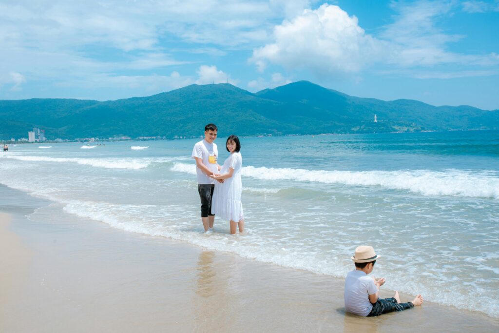 Family enjoying a sunny day at Da Nang Beach, Vietnam with mountains in the background.