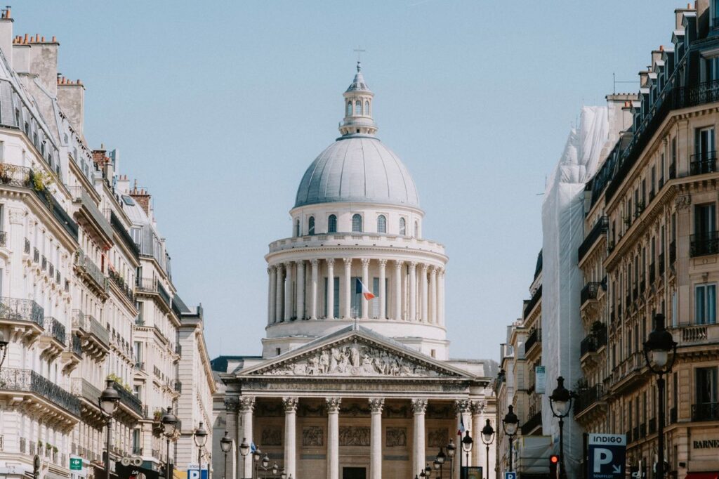 A captivating view of the Pantheon in Paris framed by classic architecture under a vibrant blue sky.