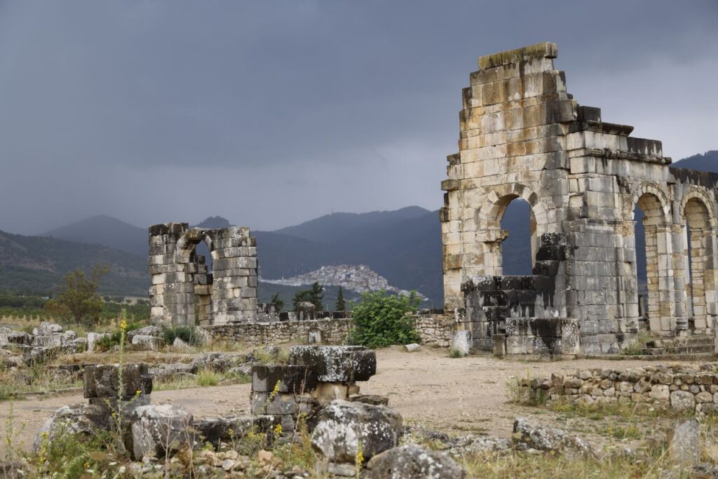 Explore the ancient Roman ruins of Volubilis, Morocco, amidst a dramatic landscape.