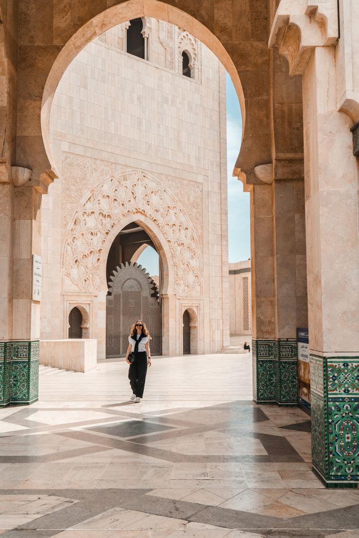 A woman strolls through the intricate architecture of Hassan II Mosque in Casablanca, Morocco.