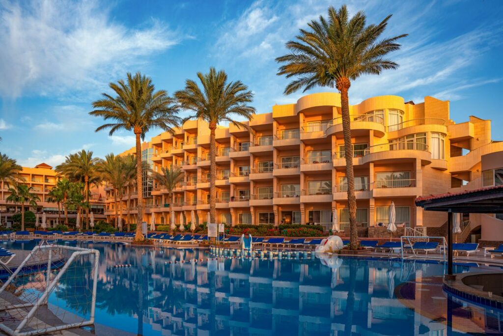 Elegant hotel with palm trees and poolside in Hurghada, Egypt during a sunny day.
