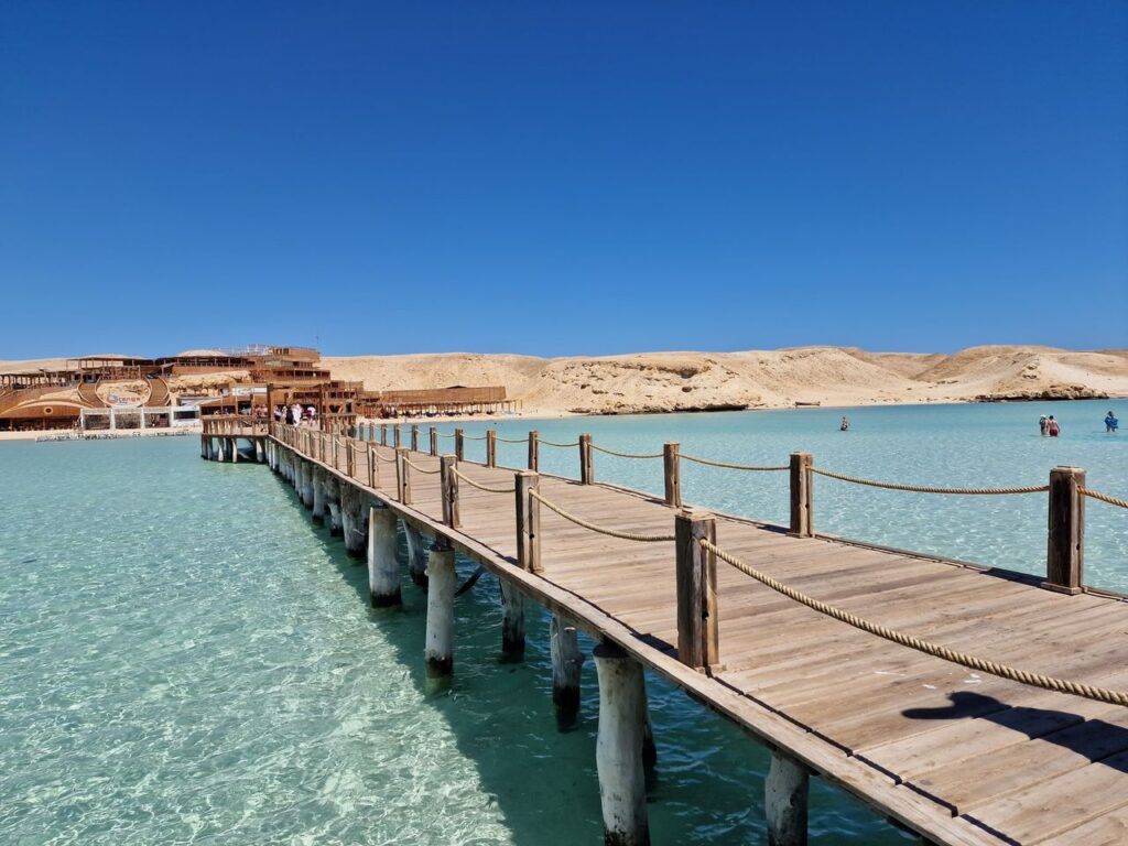 A stunning view of a wooden pier extending over clear turquoise waters against a blue sky.