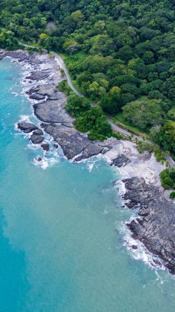A stunning aerial shot of a tropical coastline with clear blue waters and dense green forests.