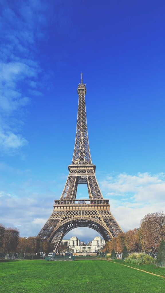 A stunning view of the Eiffel Tower in Paris, France, framed by a clear blue sky and lush greenery.