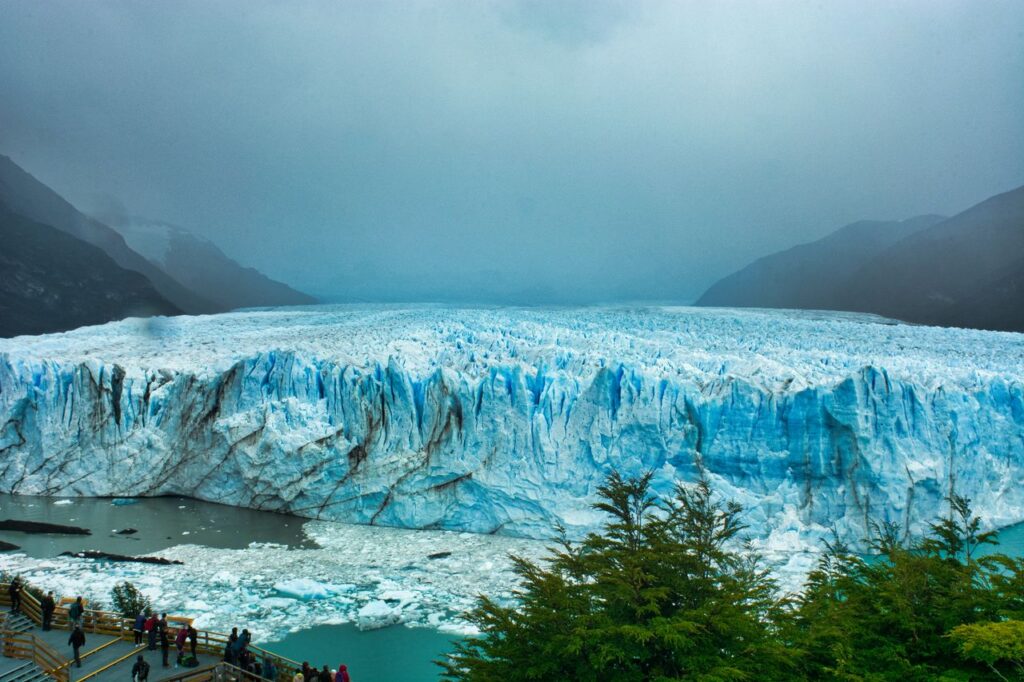 Magnificent landscape of blue glacier in highland terrain under cloudy dramatic sky in winter
